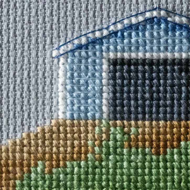 A close-up photo of the details of a cross-stitched house piece