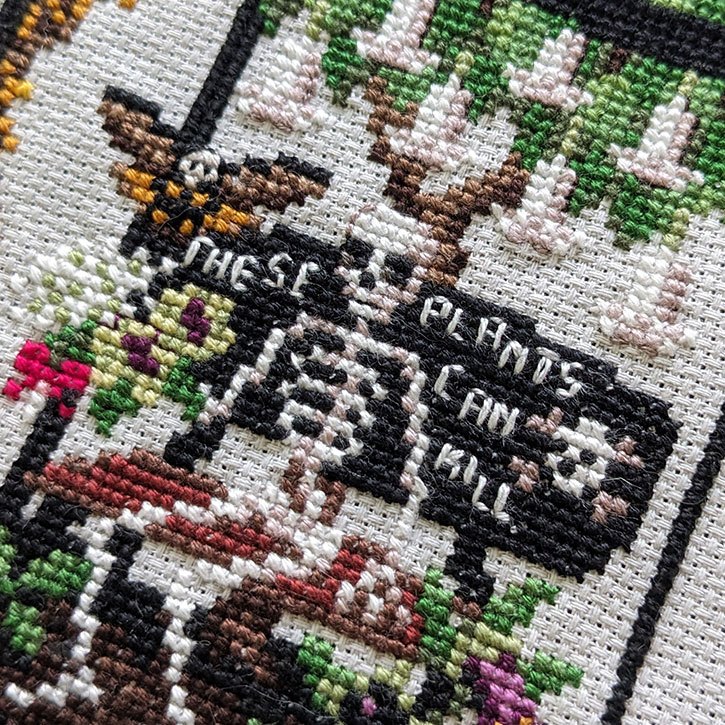 A close-up photograph of a section of the "Greenhouse of Oddities" cross-stitch piece.