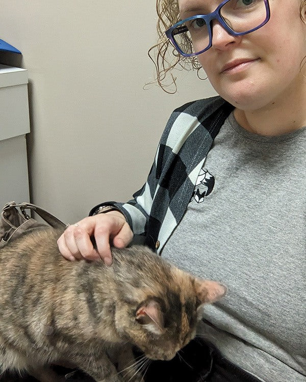 A multi-coloured cat (Zoe) cuddling Kate while waiting at the vet