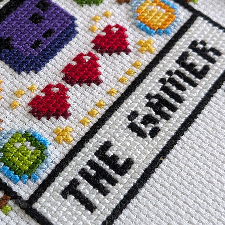 A close-up photograph of the "Gamer Tarot" cross-stitch piece