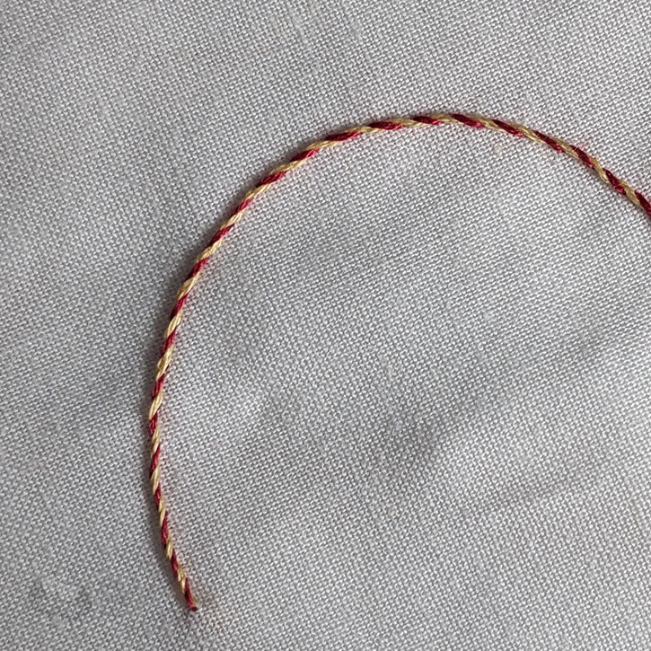 A curved, semi-circle with two colours (red and yellow) demonstrating a whipped back stitch.