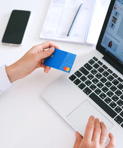 imagem de mãos em frente ao computador segurando cartão de crédito em imagem de compra online