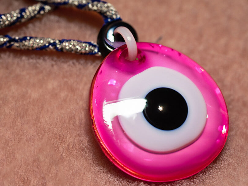 A close-up shot of a Pink Evil Eye amulet