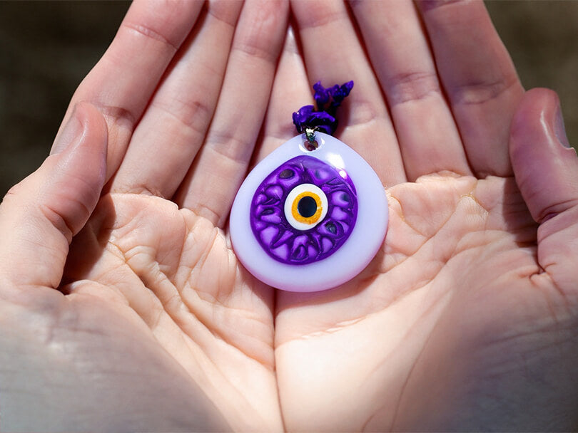 Hands Holding a Purple Evil Eye Amulet
