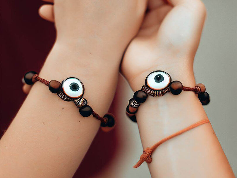 Two hands holding with Brown Evil Eye bracelets