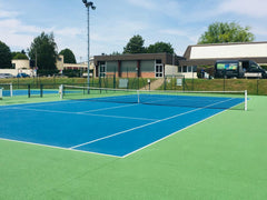 Resurfaçage en peinture d'un terrain de tennis en béton poreux, pour une rénovation esthétique et fonctionnelle de la surface de jeu.