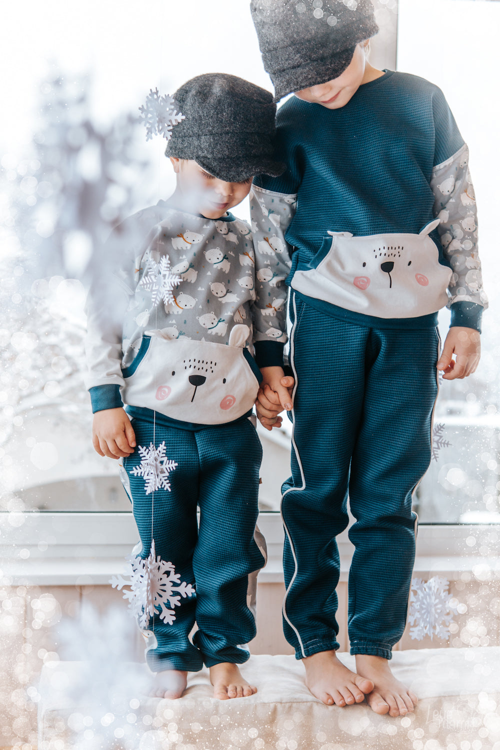 Zwei Jungs im Wohnzimmer die sich anschauen. Selbstgenähte Hosen aus Bio-Waffelstrick von faybee. Sweater aus Jersey und Waffelstrick von Faybee