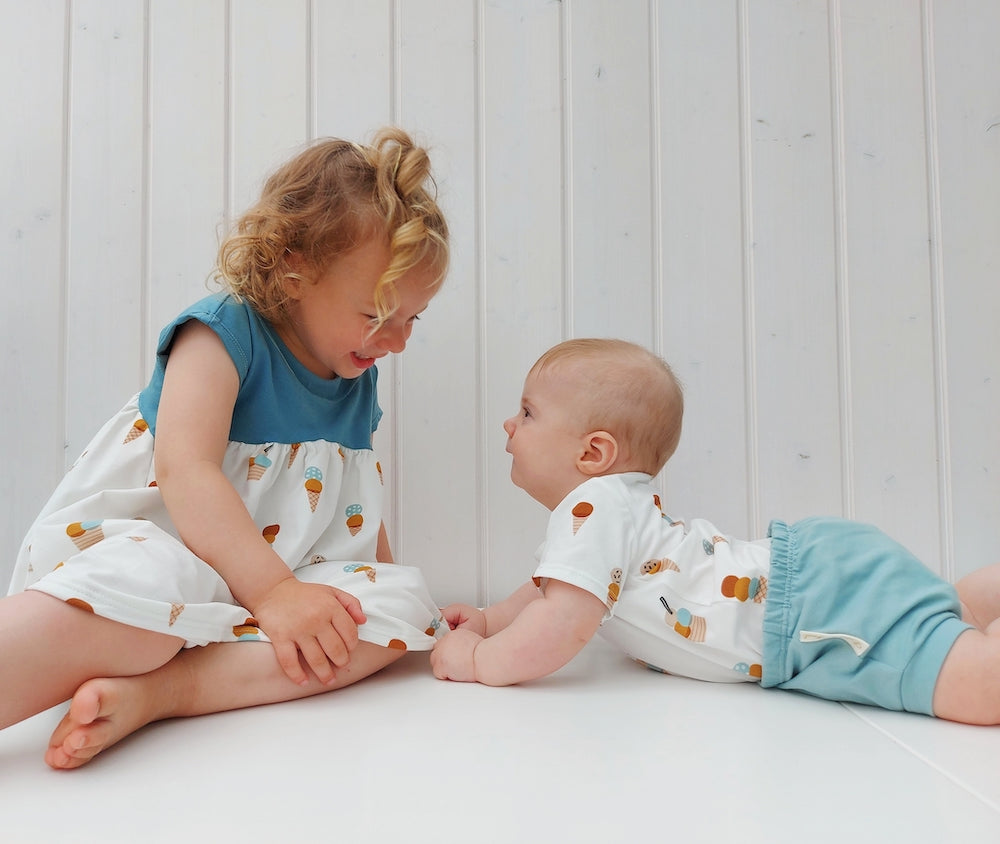 Baby und grosse Schwester reden miteinander. Sie tragen selbstgenähte Kleidung aus Biojersey von Faybee