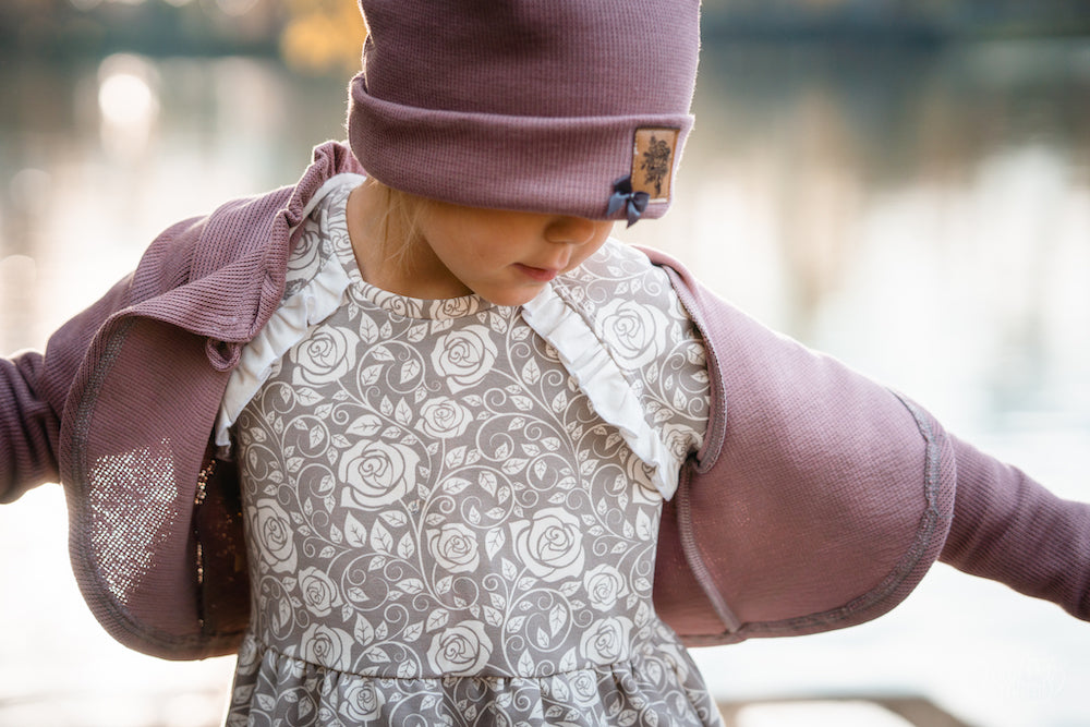 Ein Mädchen an einem See. Das Mädchen trägt ein selbstgenähtes Sweatkleid. Der Stoff ist ein Biosweat erhältlich bei faybee.ch. Dazu trägt das Mädchen einen Bolero aus Selanik in der Farbe woodrose.