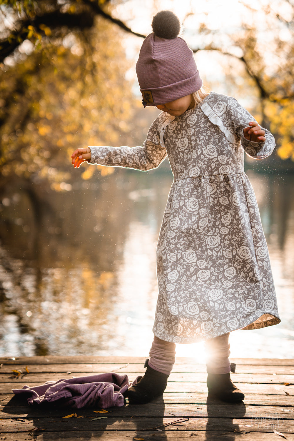 Ein Mädchen an einem See. Das Mädchen trägt ein selbstgenähtes Sweatkleid. Der Stoff ist ein Biosweat erhältlich bei faybee.ch.