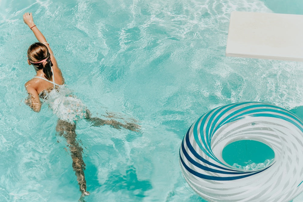 girl swimming in saltwater pool with float behind her