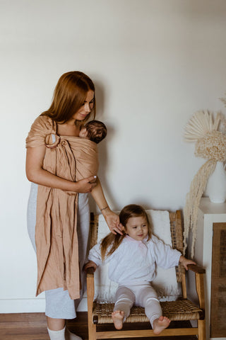 Chelsea and her daughters in the playroom. Chelsea wears a Chekoh Baby Ring Sling Carrier in Terracotta 