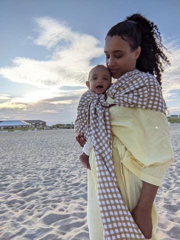 Immy on a beach with her little one, enjoying hands free snuggles with a Chekoh Ring Sling Carrier 