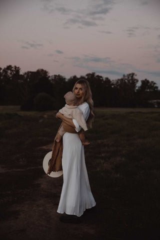 Mady Lee baby wearing in a field in a Chekoh Ring Sling Carrier in Camel colour