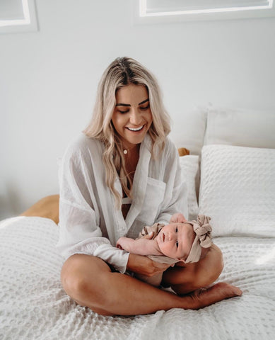 Smiling Mum Liv is looking lovingly at her daughter Halo wearing a Chekoh Baby Pocket with a Bow in Cinta