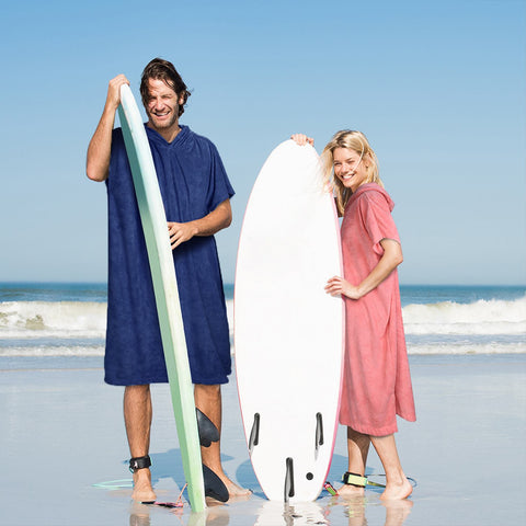 A couple with surfboards and surf poncho towels on a happy date at the beach