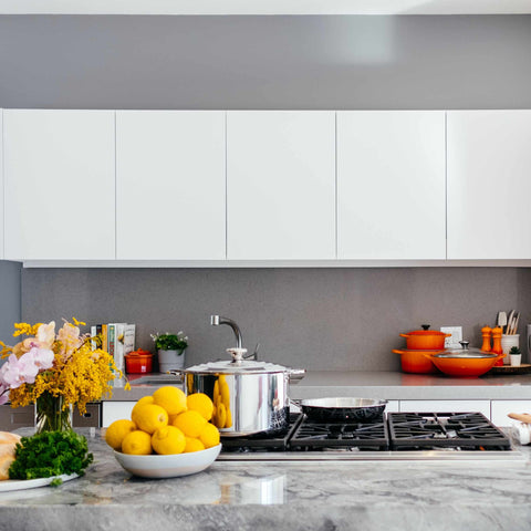 An industrial kitchen, open plan, with fruit, white cabinets and cutlery