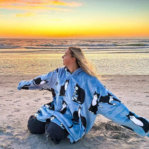 Digital creator in IG, enjoying the ocean breeze at sunset wearing a blue and gray wonder cat hooded blanket.
