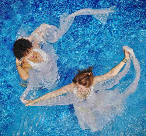 Two girls dancing in the water of the pool