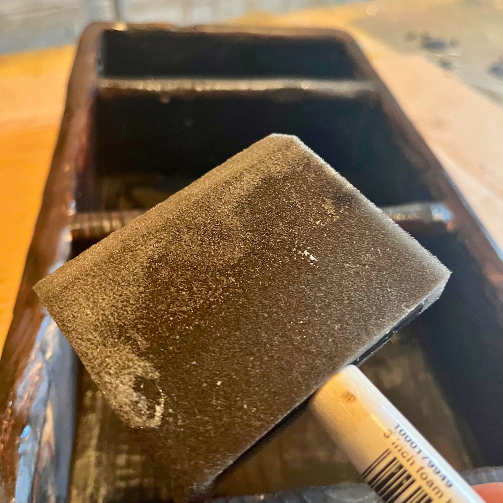 Close up of a foam brush with the miniature bookshelf in the background.