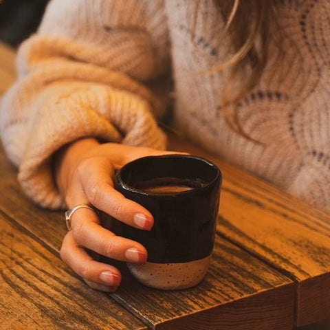 Women in knit jumper holds Lil Ceramics tumbler with a hot drink