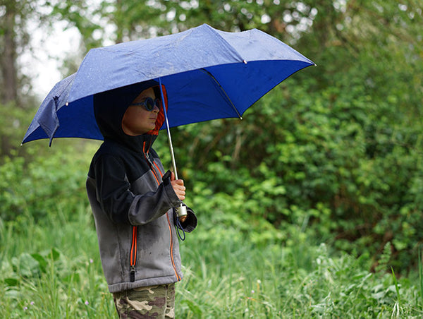 A happy little outdoor boy with an umbrella