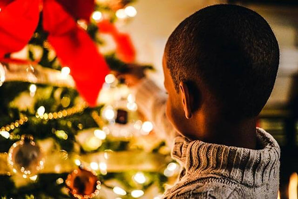 Boy reaching toward brightly lit Christmas tree