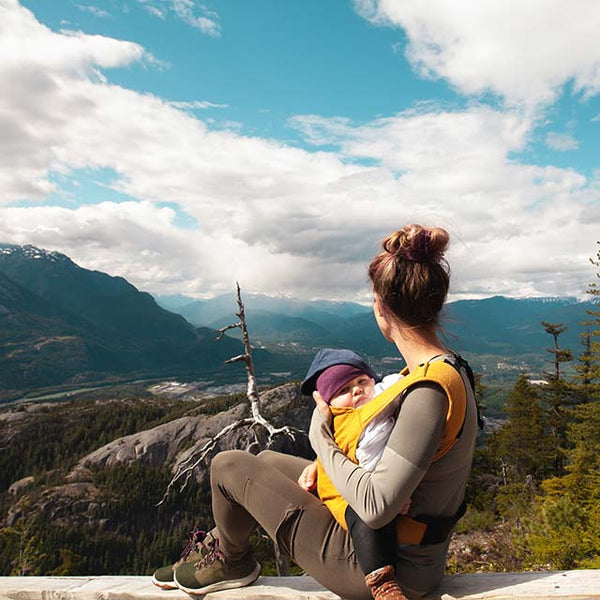 A woman and baby resting on a bench overlooking a mountainous view