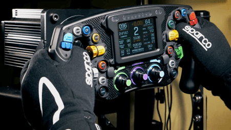 F1 style sim racing steering wheel up close with someone gripping the handles