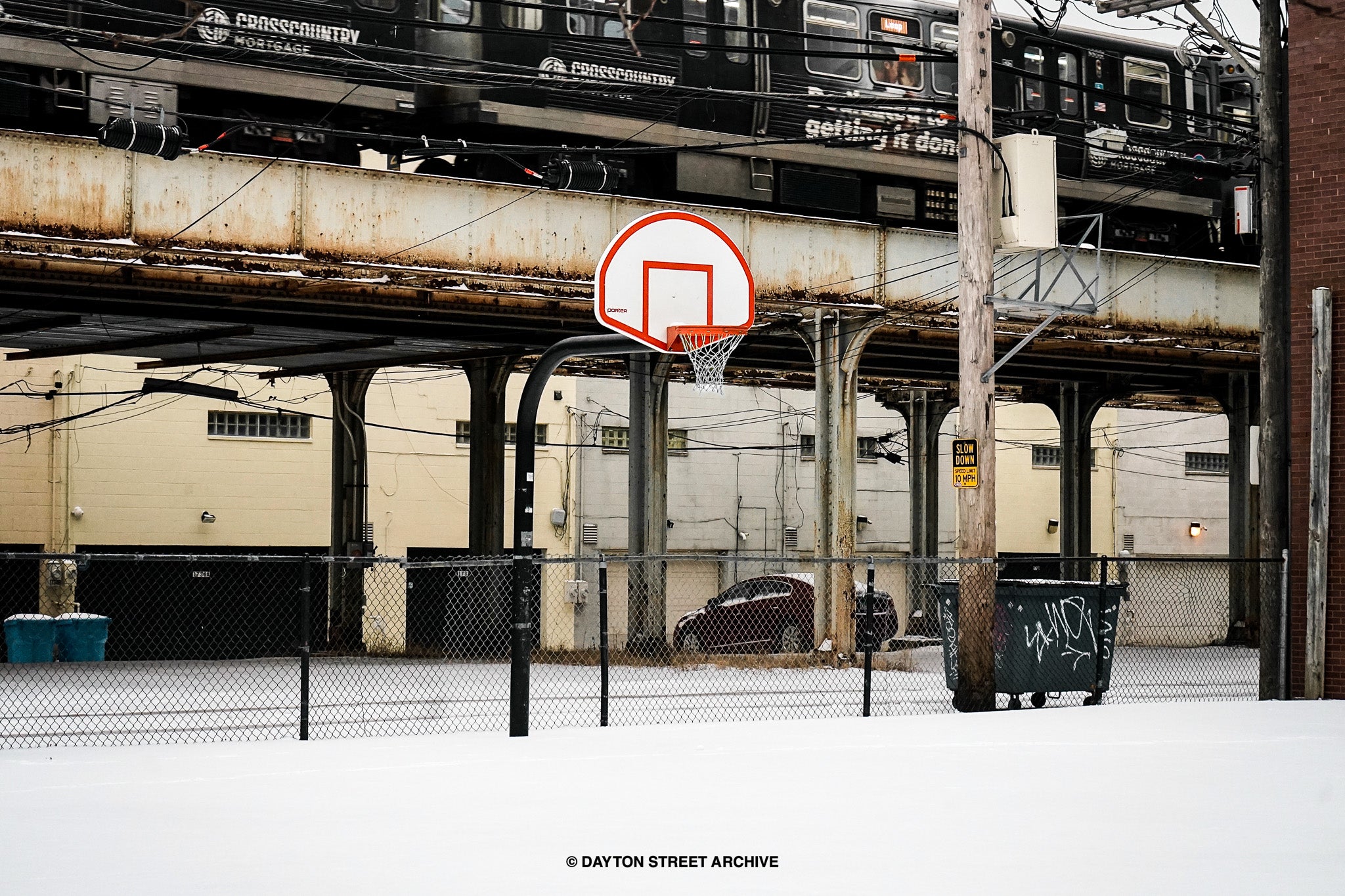 Basketball hoop in front of Chicago train tracks with snow