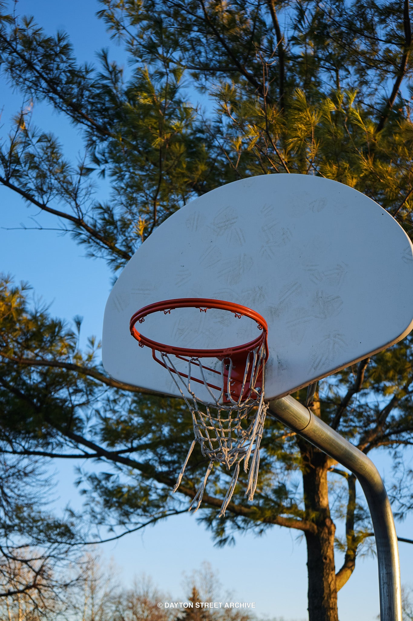 high quality up close basketball hoop with worn net with blue sky and trees