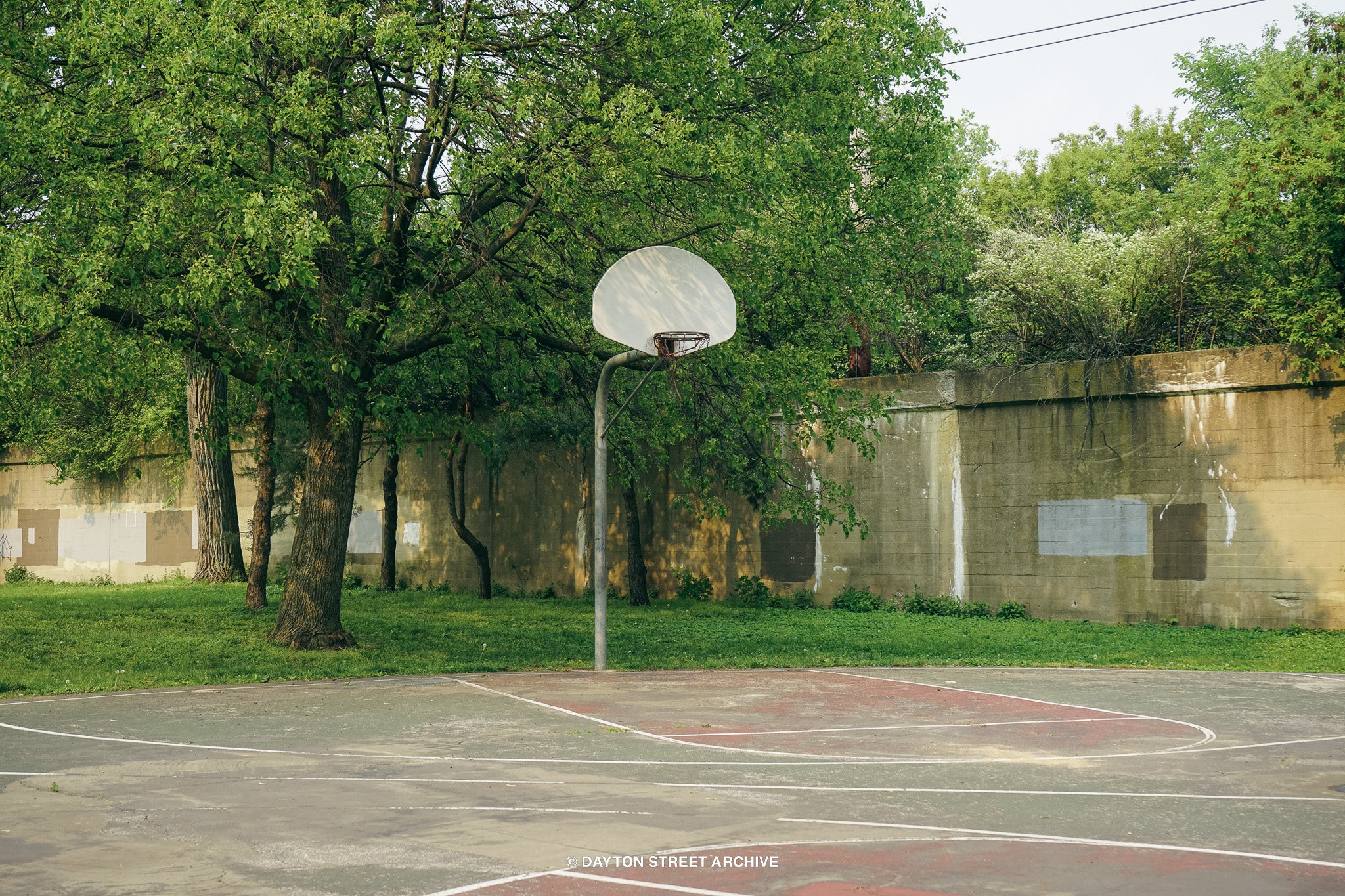 vintage urban basketball court photograph with trees and train rails in background