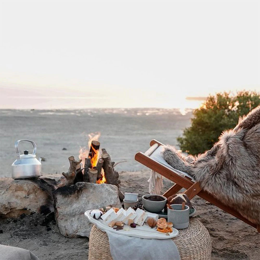 Custom ceramic platter featured in a outdoor picnic scene with fire, seating, and appetizers