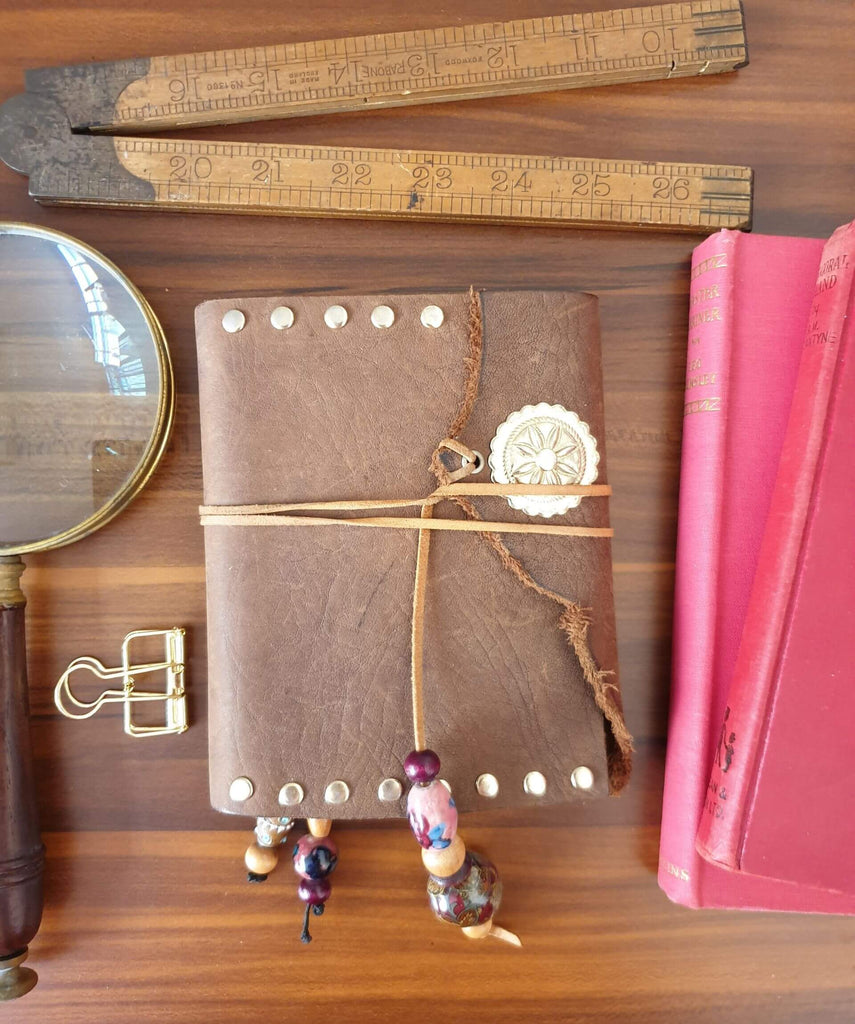 brown leather journal  on desk with vintage stationery