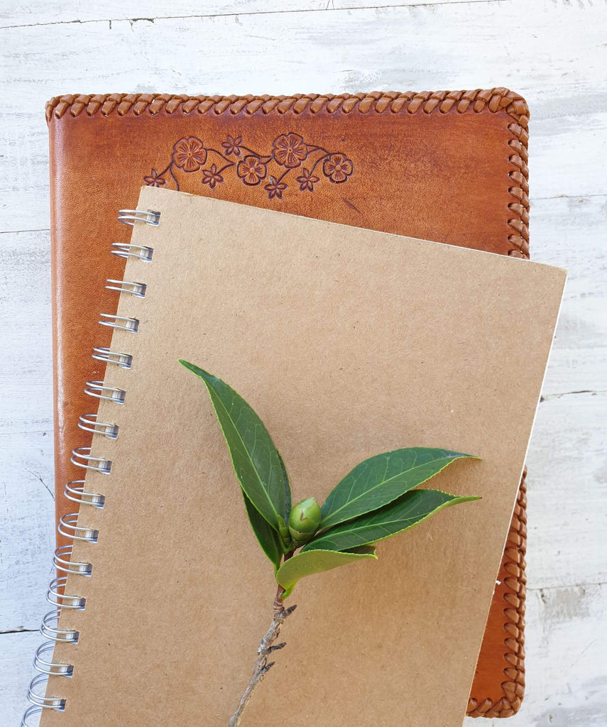 flower bud and leaves on natural paper notebook and leather journal