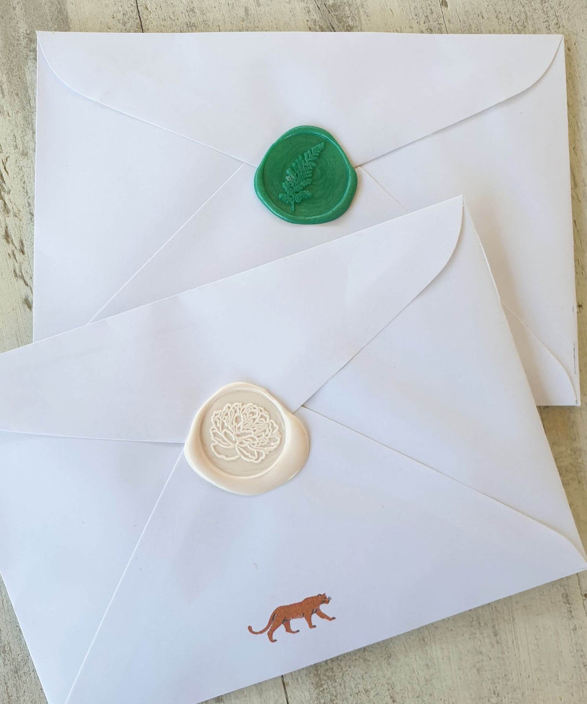 two envelopes sealed with wax seals in green and pink wax