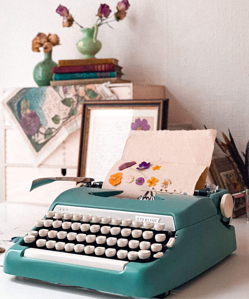 eclectic desk with vintage typewriter and dried flowers
