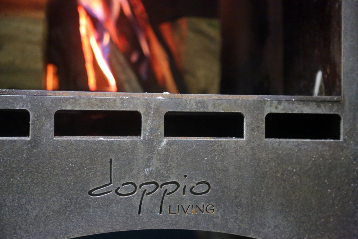 Doppio Living wood fired pizza oven with a fire going inside