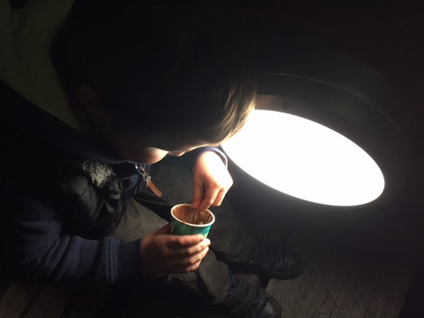 Little boy eating ice-cream with a spoon at night by a floodlight
