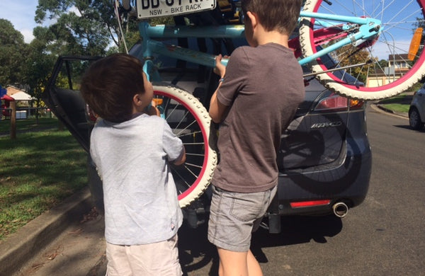 Picture of two junior recipe testers helping load bikes onto a bike rack