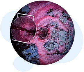 An aerial view shows red liquid pouring from a container into a larger body, creating pink foam reminiscent of the Patriot XL Skid-Mounted Turnkey Reverse Osmosis System by US Water Systems Inc.