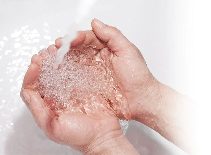 Man drinking from his hands using water from the sink