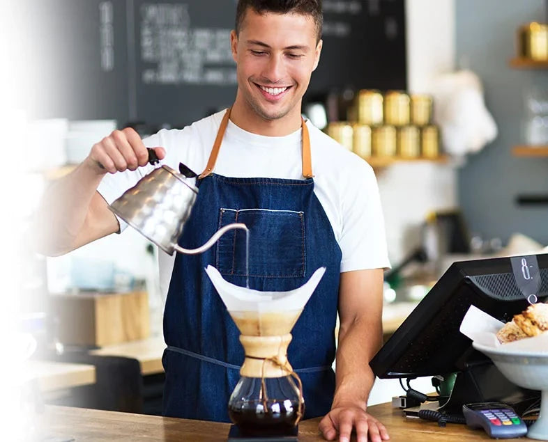 Man in Coffee Shop making a latte by hand