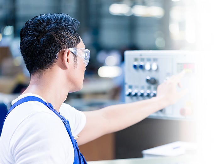 Man Running a Machine in a Factory Setting