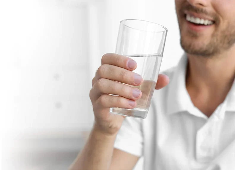 Man smiling while drinking a glass of crystal clear water