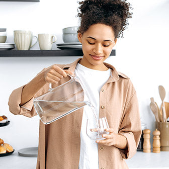 Woman Pouring Water Into a Glass