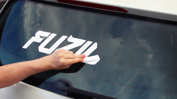 a person removing transfer sticker from a car