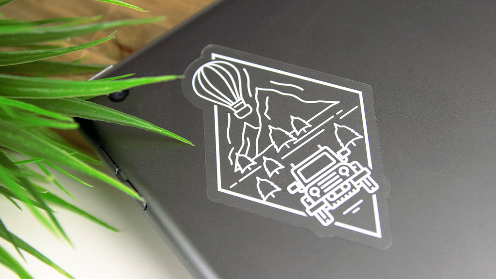 Clear die cut adventure logo applied to a silver laptop