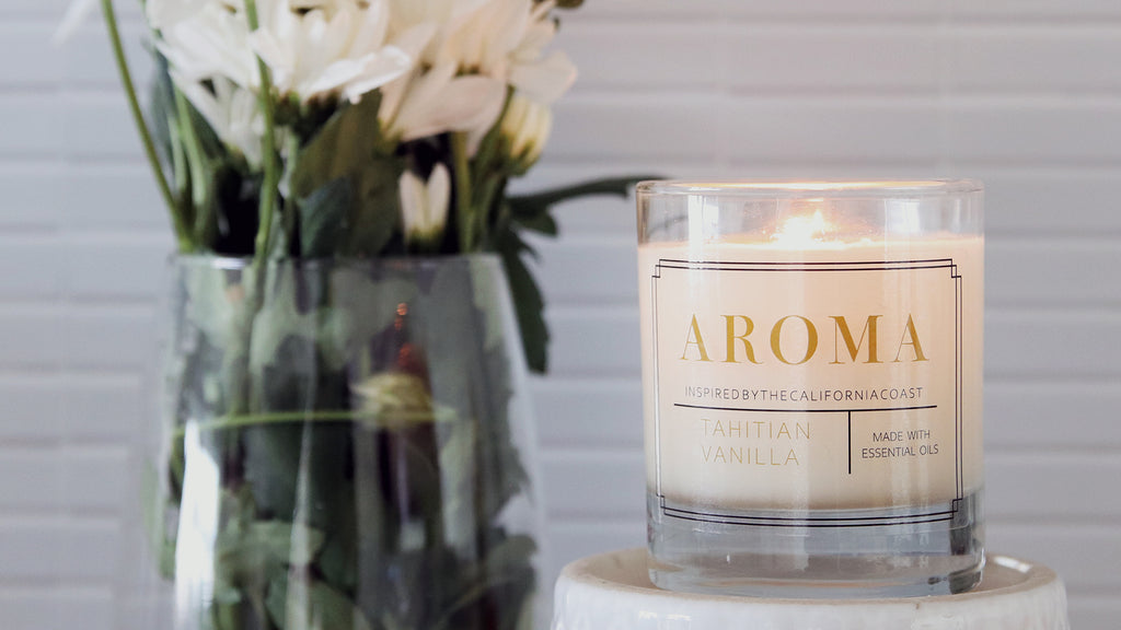 Clear rounded corner sticker applied to a clear candle jar with a white candle next to white flowers in a vase