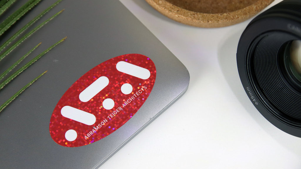 https://cdn.shopify.com/s/files/1/0735/4984/0659/files/oval-glitter-sticker-with-red-ata-logo-applied-to-a-silver-laptop_1024x1024.jpg?v=1681734228